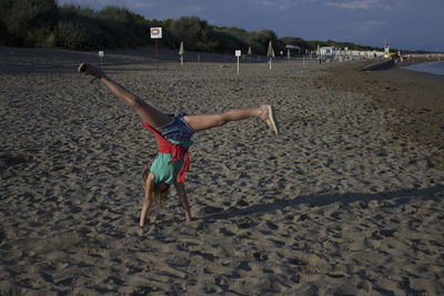 Girl doing handstand on sand at beach