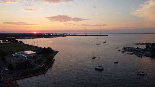 Sailboats in sea at sunset