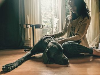 Young woman sitting by dog at home