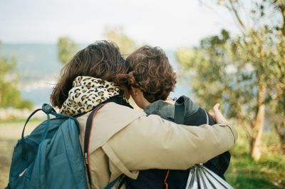 Rear view of women embracing standing outdoors