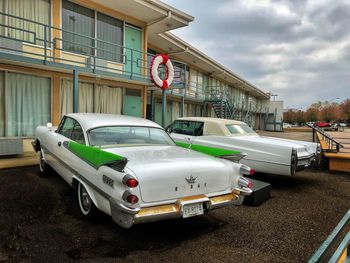 Cars on road by buildings in city against sky