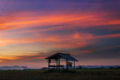 Built structure on field against sky at sunset