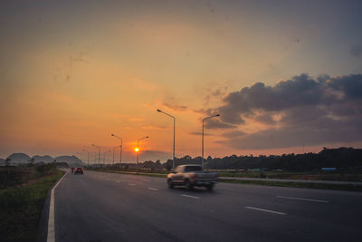 Cars on road against sky during sunset