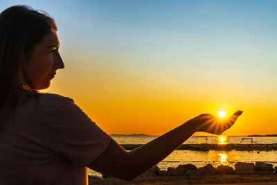 Woman looking at sea against sky during sunset