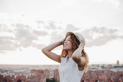 Portrait of young woman standing against sky