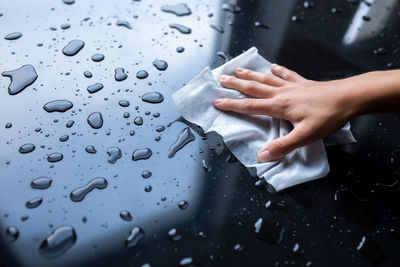 Close-up of hand touching wet glass