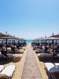 People on beach against clear blue sky