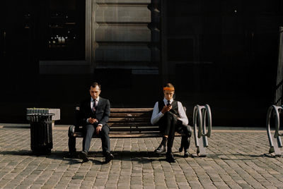 Men sitting on bench in city at night