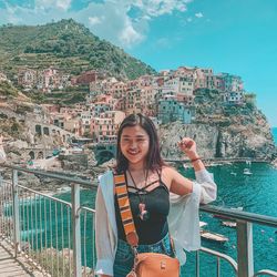 Portrait of smiling young woman standing against railing