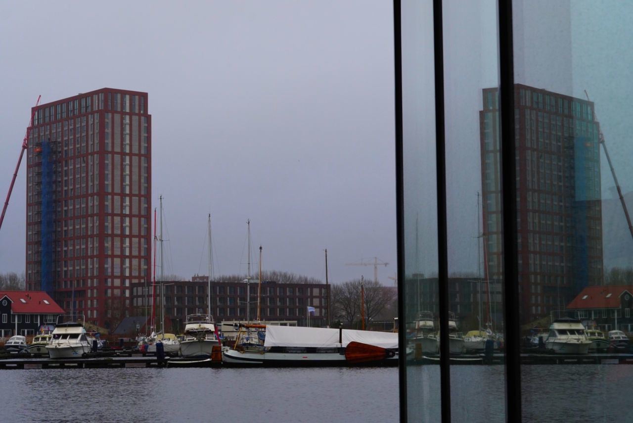 building exterior, architecture, nautical vessel, transportation, water, built structure, mode of transportation, sky, city, day, no people, nature, waterfront, building, moored, clear sky, harbor, sailboat, reflection, modern, outdoors, office building exterior, skyscraper