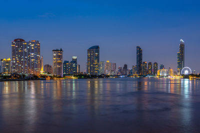 Illuminated buildings in city against sky at night