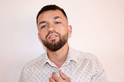 Portrait of young man standing against white background