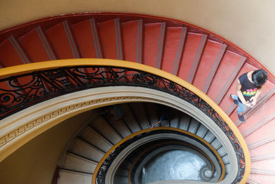 High angle view of man moving down on red staircase in building