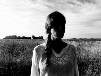 Portrait of woman standing on field against sky
