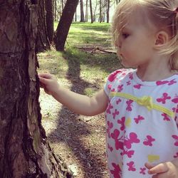 Portrait of cute girl holding tree trunk