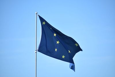 Low angle view of blue flag against clear sky