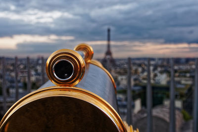 Close-up of coin operated binoculars over cityscape against sky