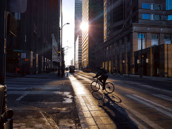 Cars on city street by buildings against sky