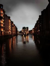 Buildings by river against sky at night