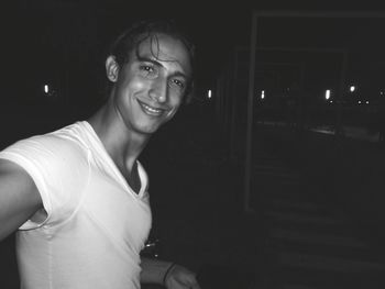 Portrait of smiling young man standing outdoors at night