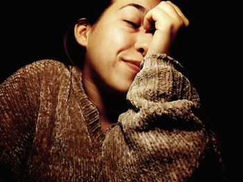 Close-up of young woman against black background