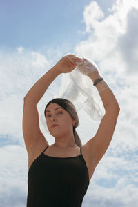 Young woman looking away while standing against sky