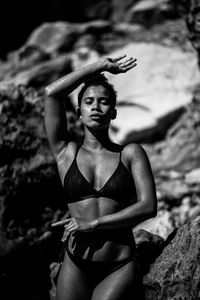 Young woman with arms raised on rock