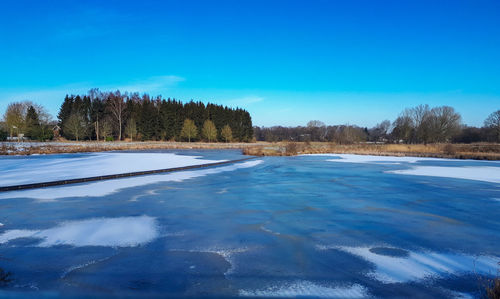 Scenic view of frozen lake against blue sky