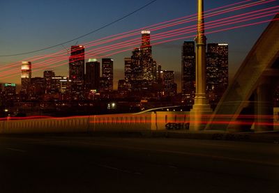 Light trails on road against illuminated built structures