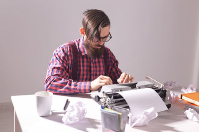 Mid adult man sitting on table against wall