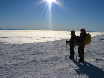 People standing at frozen beach against sky