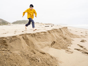 Young person running toward sandy ledge at california beach