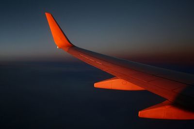 Close-up of airplane wing against sky during sunset
