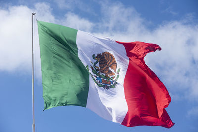 Low angle view of woman flag against blue sky