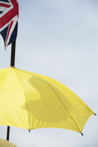 Low angle view of british flag on yellow umbrella against sky during sunny day