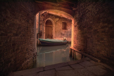 Boat moored in canal against wall