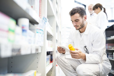 Pharmacist with pill box and prescription in pharmacy