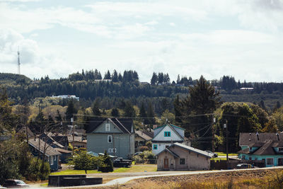 Houses amidst trees and buildings against sky
