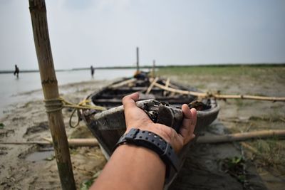 Low section of person holding hands on land against sky