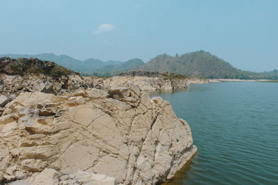 Scenic view of rocks on sea shore against sky