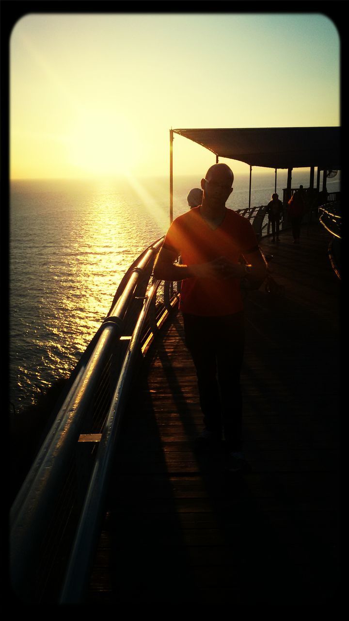 sea, water, transfer print, lifestyles, horizon over water, leisure activity, clear sky, sunset, sun, sunlight, sky, auto post production filter, men, rear view, pier, nautical vessel, person, full length