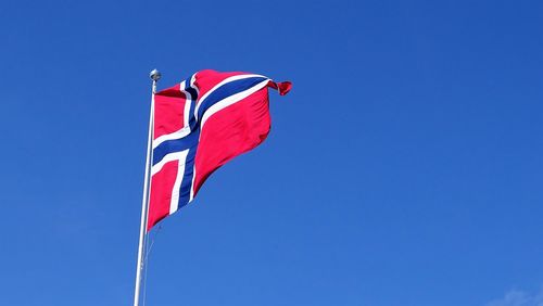 Low angle view of norwegian flag against clear blue sky