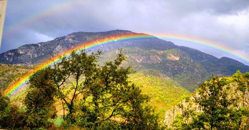 Scenic view of rainbow over mountain against sky