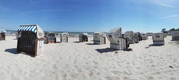 Hooded chairs on beach against blue sky