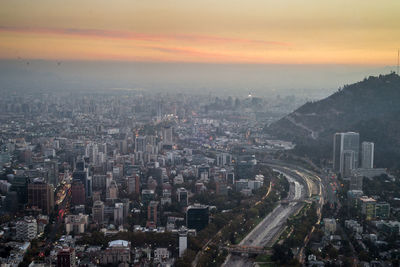 High angle view of illuminated city buildings against sky during sunset