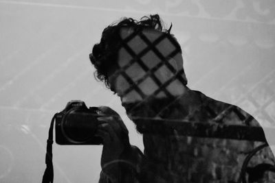 Double exposure of man holding camera and fence