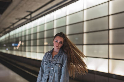 Portrait of young woman standing at railroad station platform