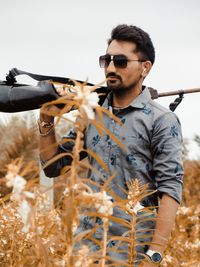 Young man wearing sunglasses standing on field