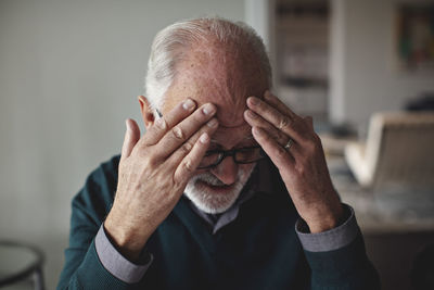 Worried senior man with head in hands at home