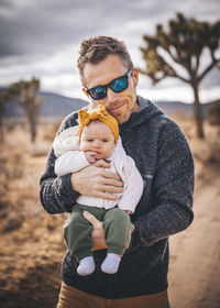 A man with a baby is standing in a desert of california